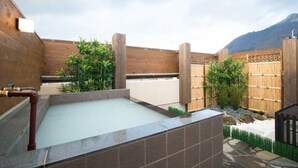 A spa area with a hot tub, wooden walls, bamboo fence, and a mountain view. - Etavia Yufuin ekimae (Yufu)