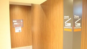 Un couloir aux murs lambrés, avec des panneaux indiquant l’emplacement des chambres à capsules réservées aux femmes.