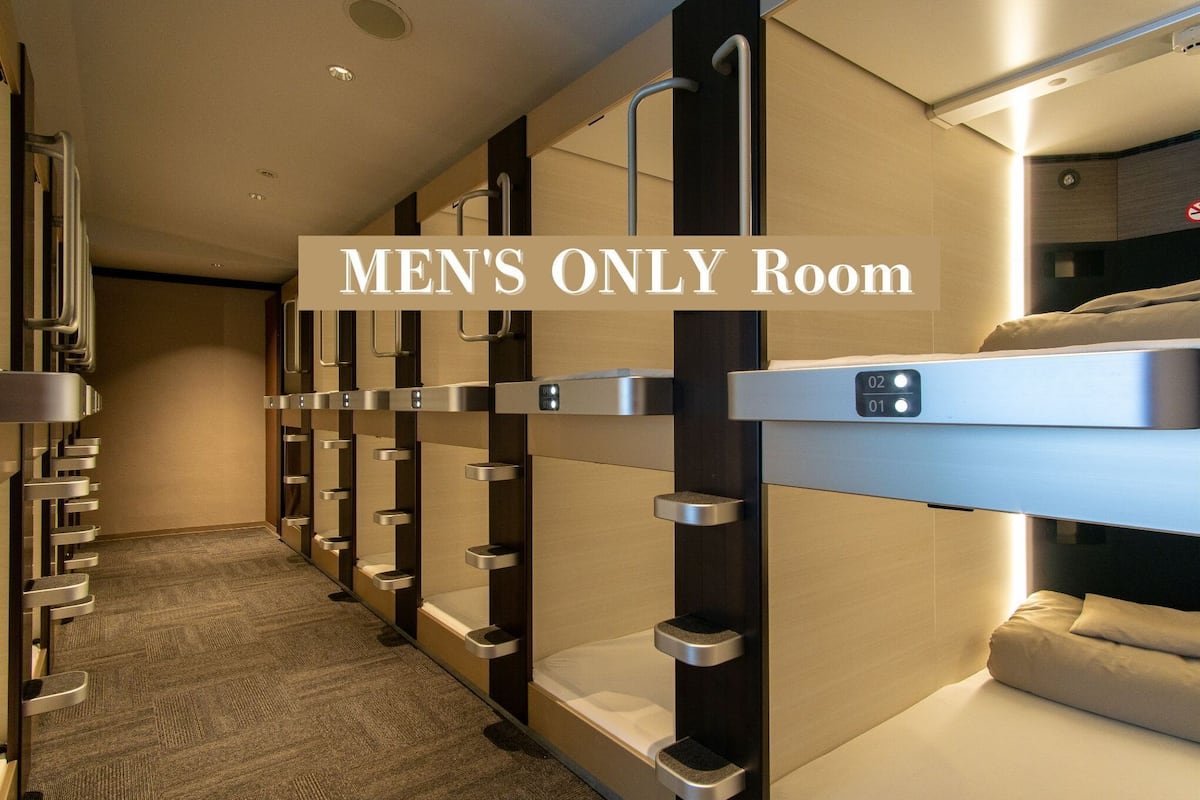 A men's only room with bunk beds, a control panel, and a carpeted floor.