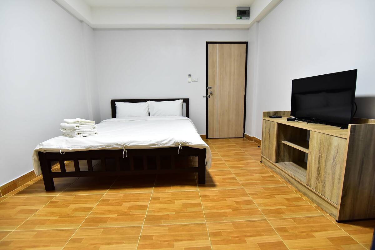 A bedroom with a bed, a television, and a wardrobe.