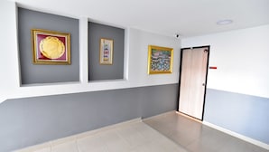 A hallway with grey and white walls, tiled flooring, and three framed artworks. - WJ Residence at Suvarnabhumi (Bang Phli)