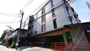 A multi-story building with a flat facade, multiple windows, and a visible garage entrance. - WJ Residence at Suvarnabhumi (Bang Phli)