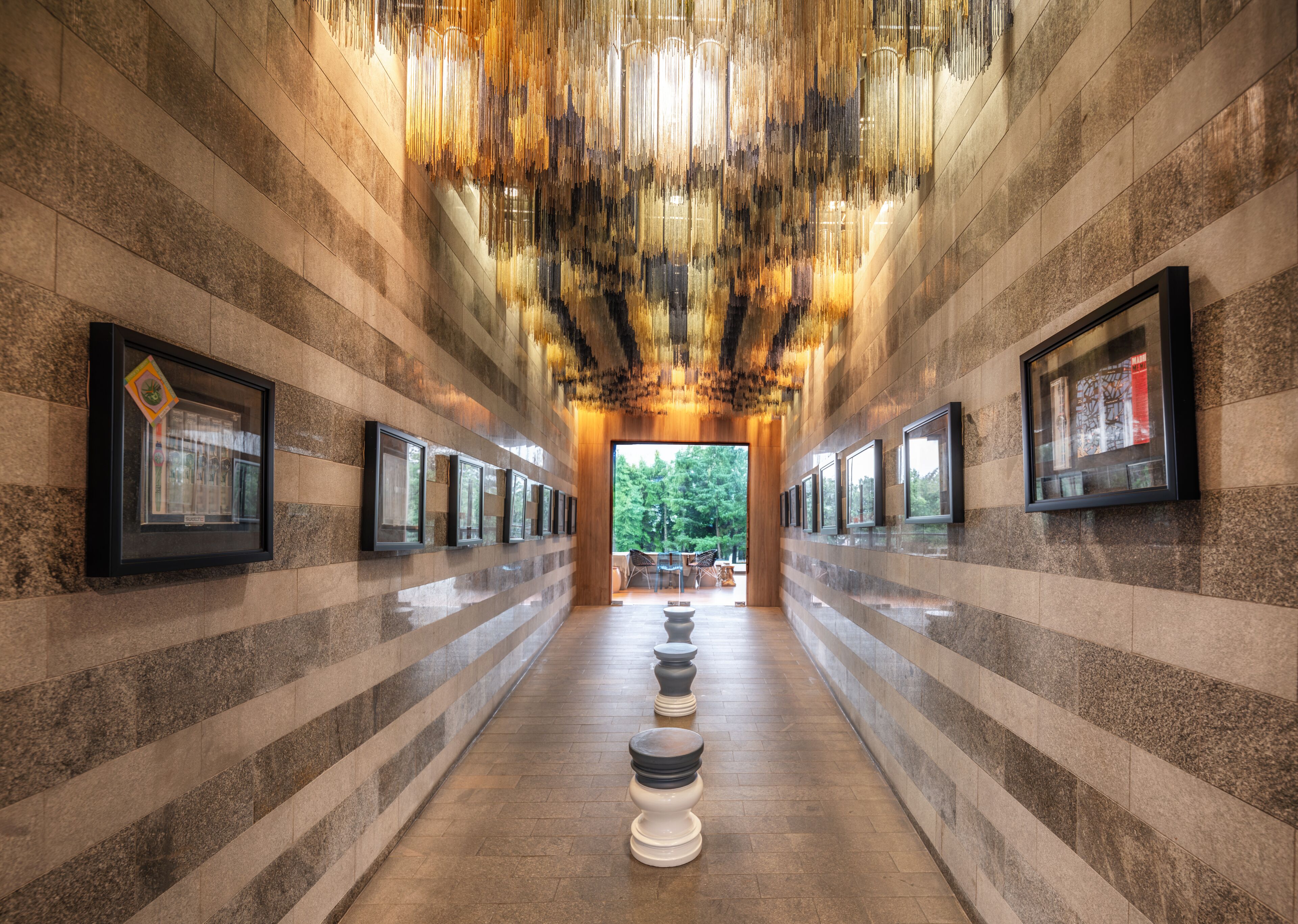 A corridor with framed pictures on the walls, a patterned floor, and a unique ceiling design.