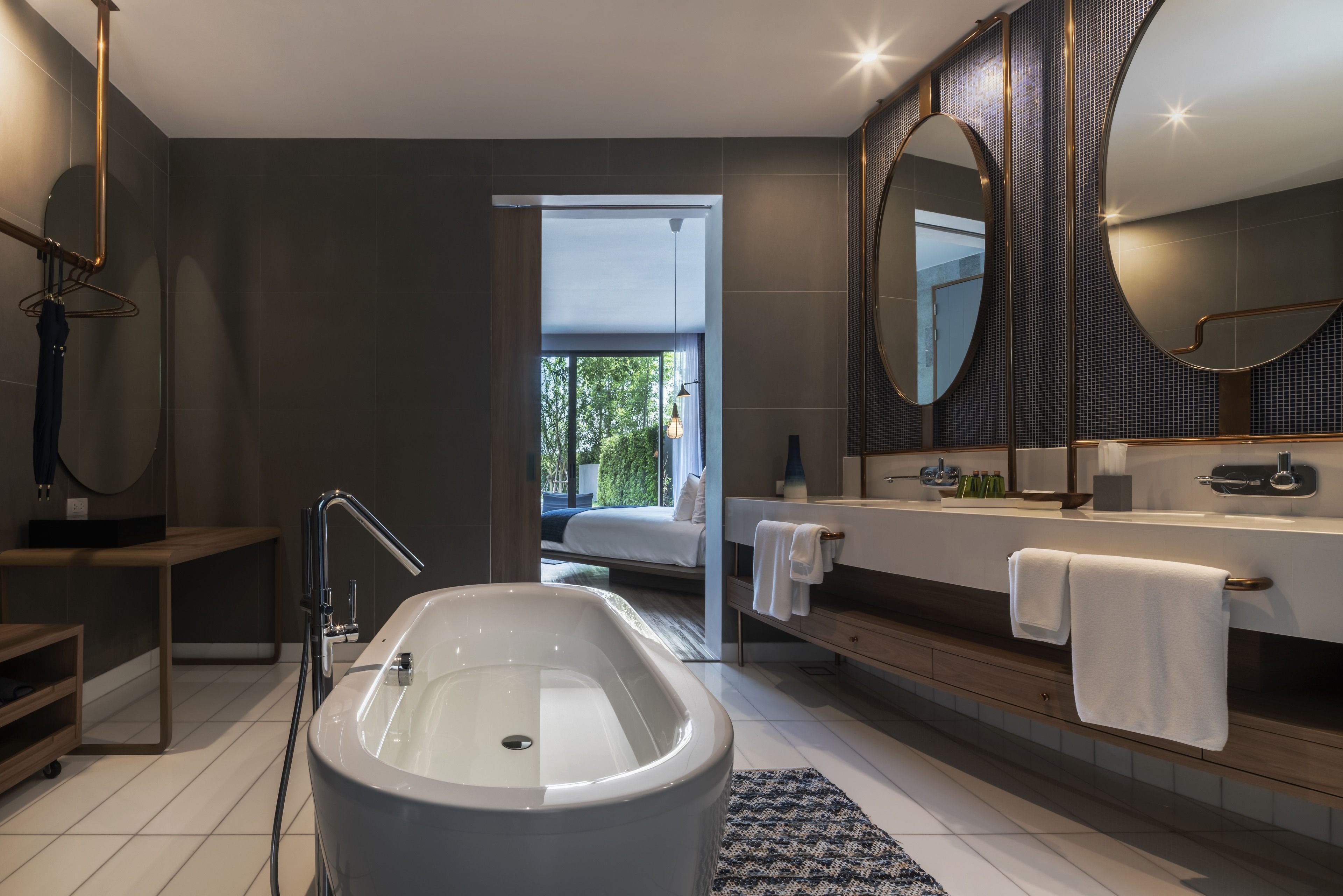 A modern bathroom with a bathtub, a large mirror, and a shower area.