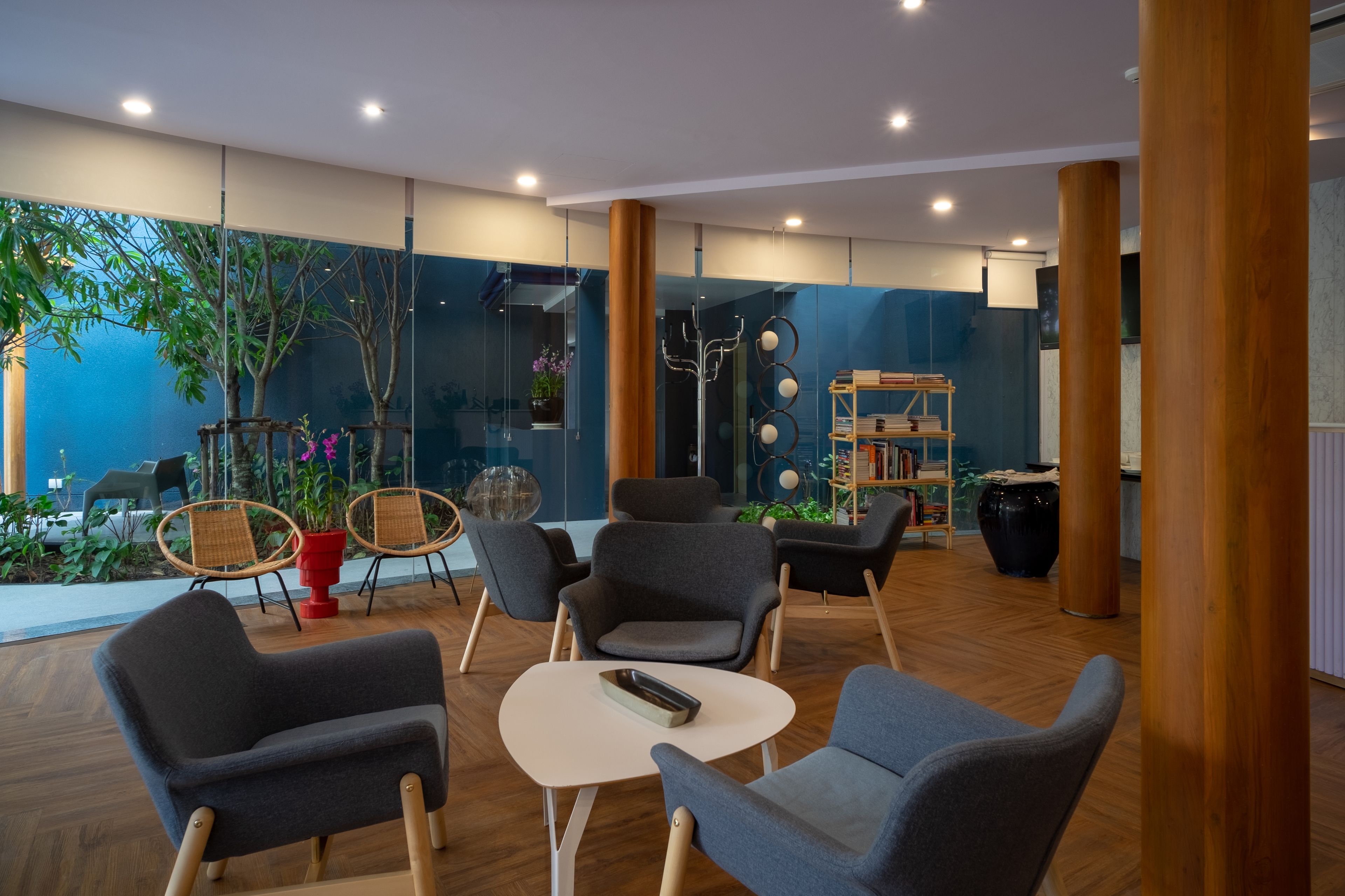 Un espacio interior moderno con asientos, una mesita y un muro de cristal con plantas.