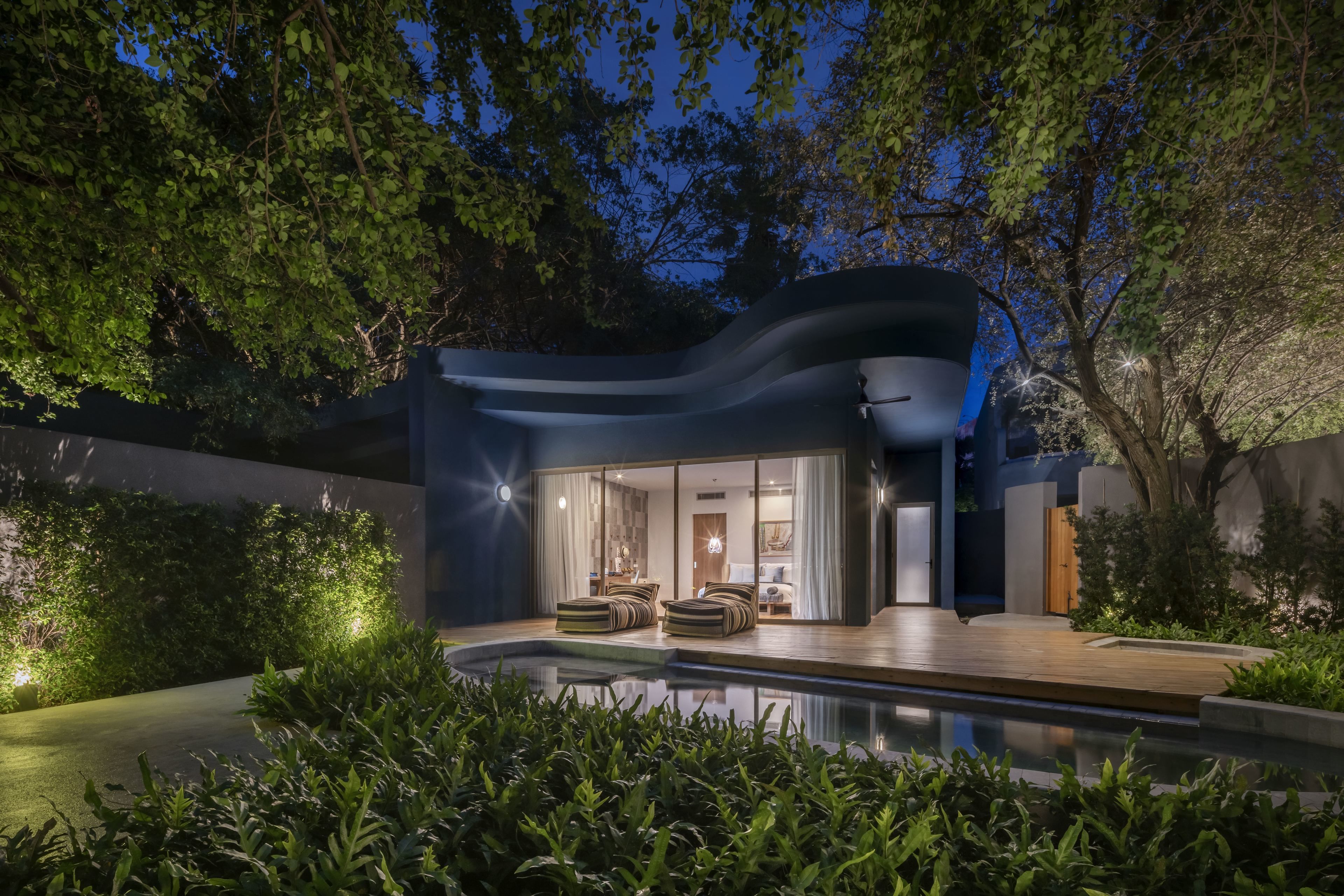 A modern house with a swimming pool, large windows, and a well-lit interior.
