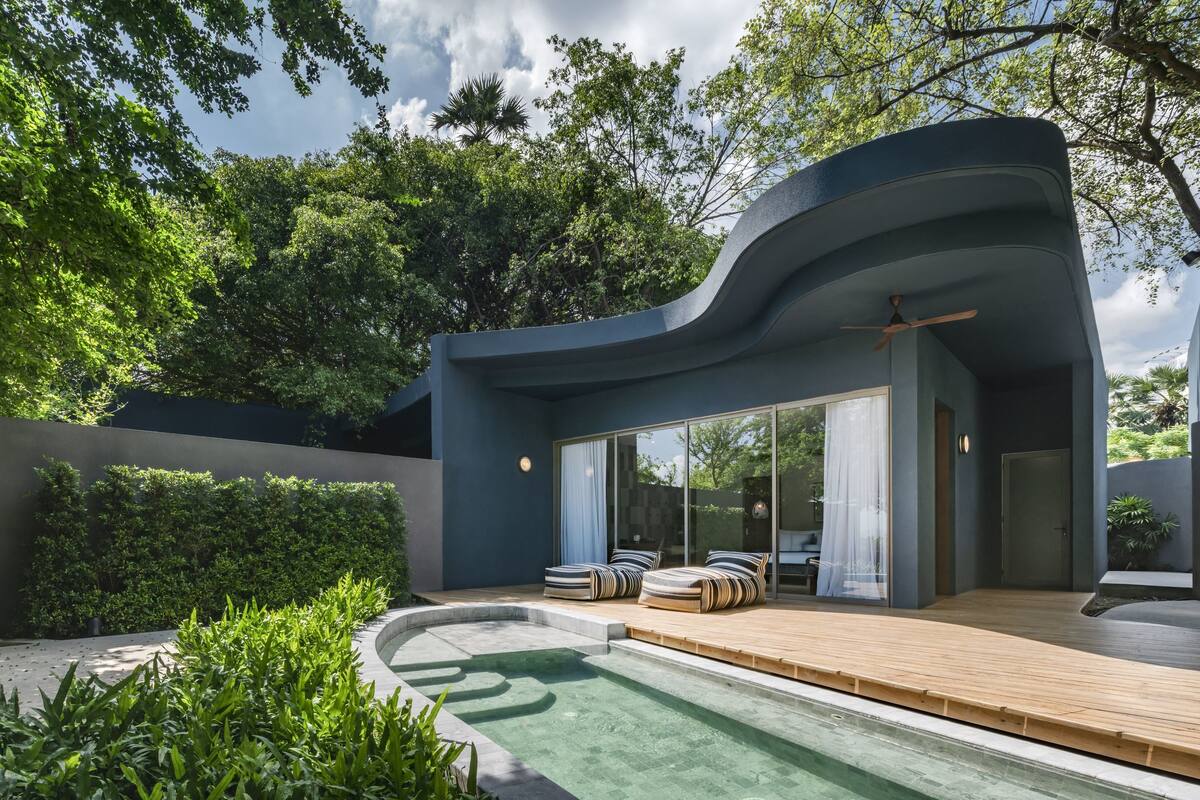 A modern house with a swimming pool, outdoor seating, and a large glass door.