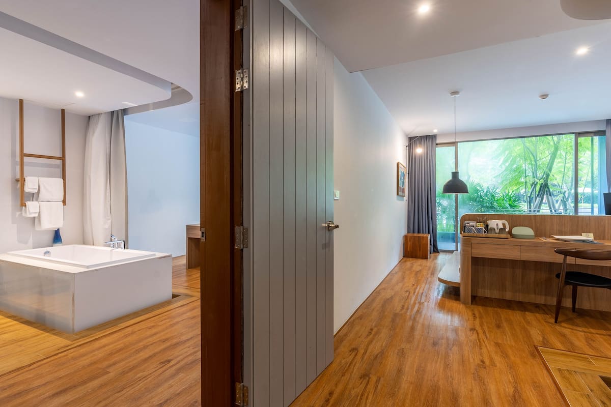 A modern bathroom with a large bathtub and a wooden floor.