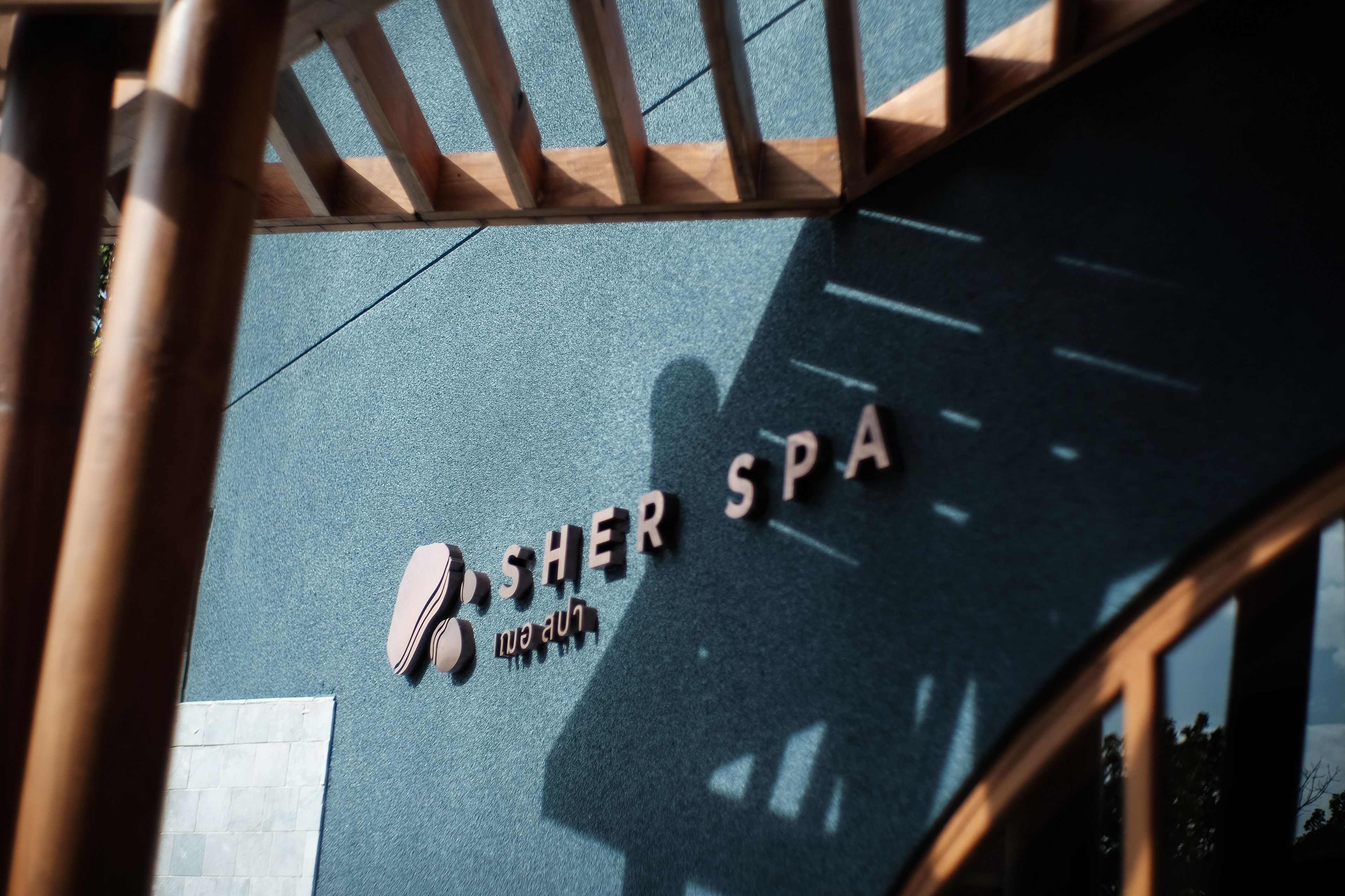 Una spa con una struttura in pergola di legno e un cartello con scritto "SHER SPA".