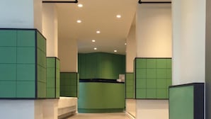 A modern interior with a staircase leading to a green kitchen area. - L42 Hostel (Bangkok)
