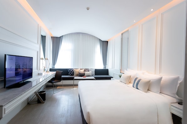 A modern hotel room with a large bed, a flat-screen TV, a desk, and a sofa. - De Princess Hotel Udonthani (Udon Thani)