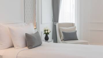 A neatly arranged bedroom with a bed, a chair, and a vase of flowers.