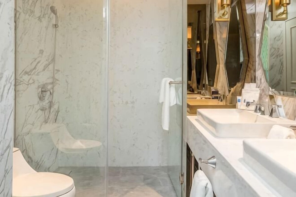 Une salle de bain avec une douche à parois de verre, des toilettes et un meuble-lavabo avec un miroir et un évier.