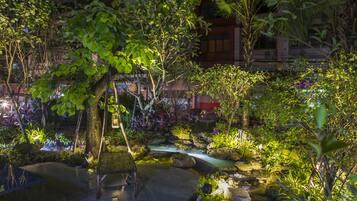 A serene garden with a wooden bench, a small water feature, and lush greenery.