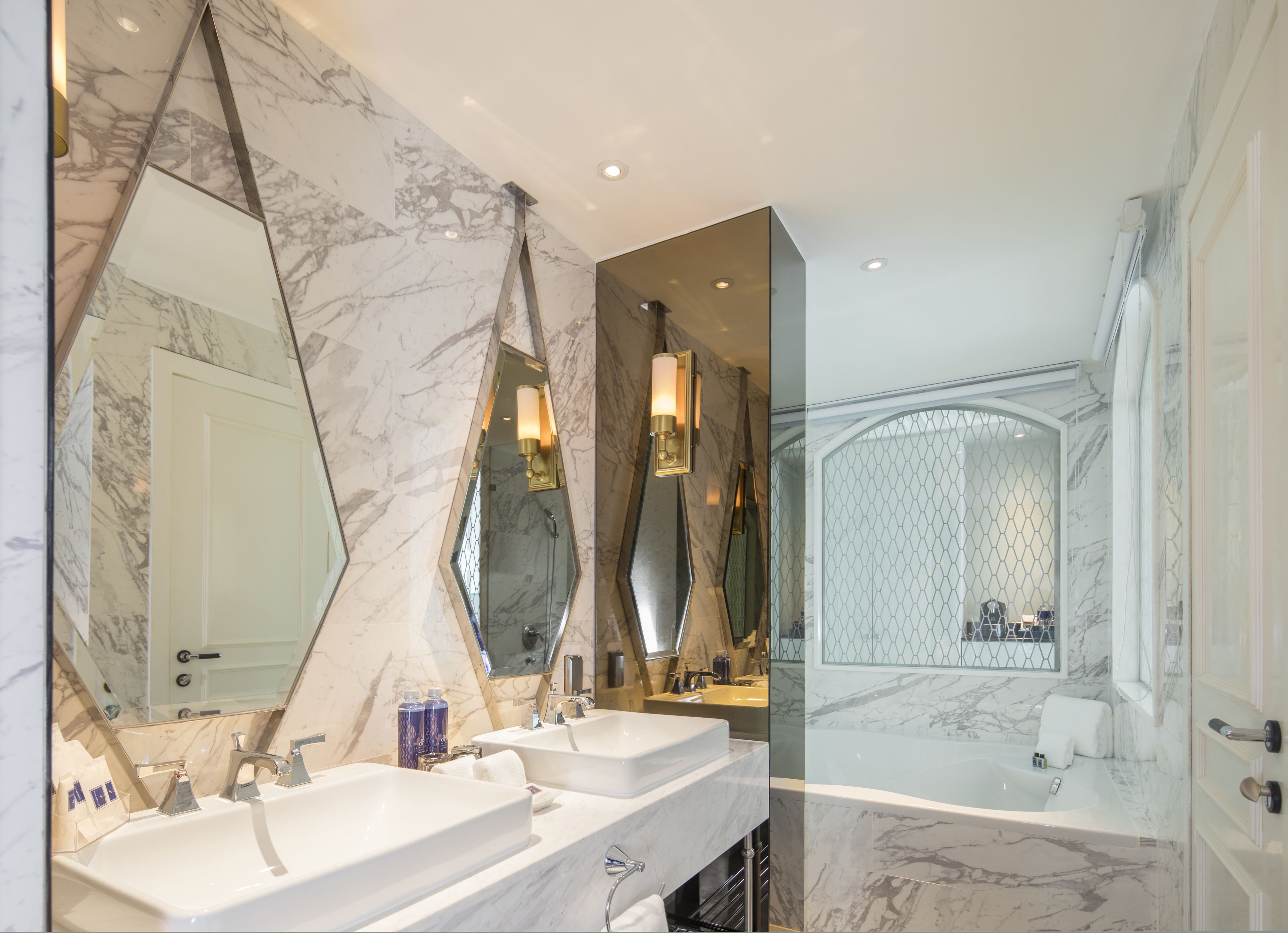 A modern bathroom with two sinks, a large mirror, and a bathtub.