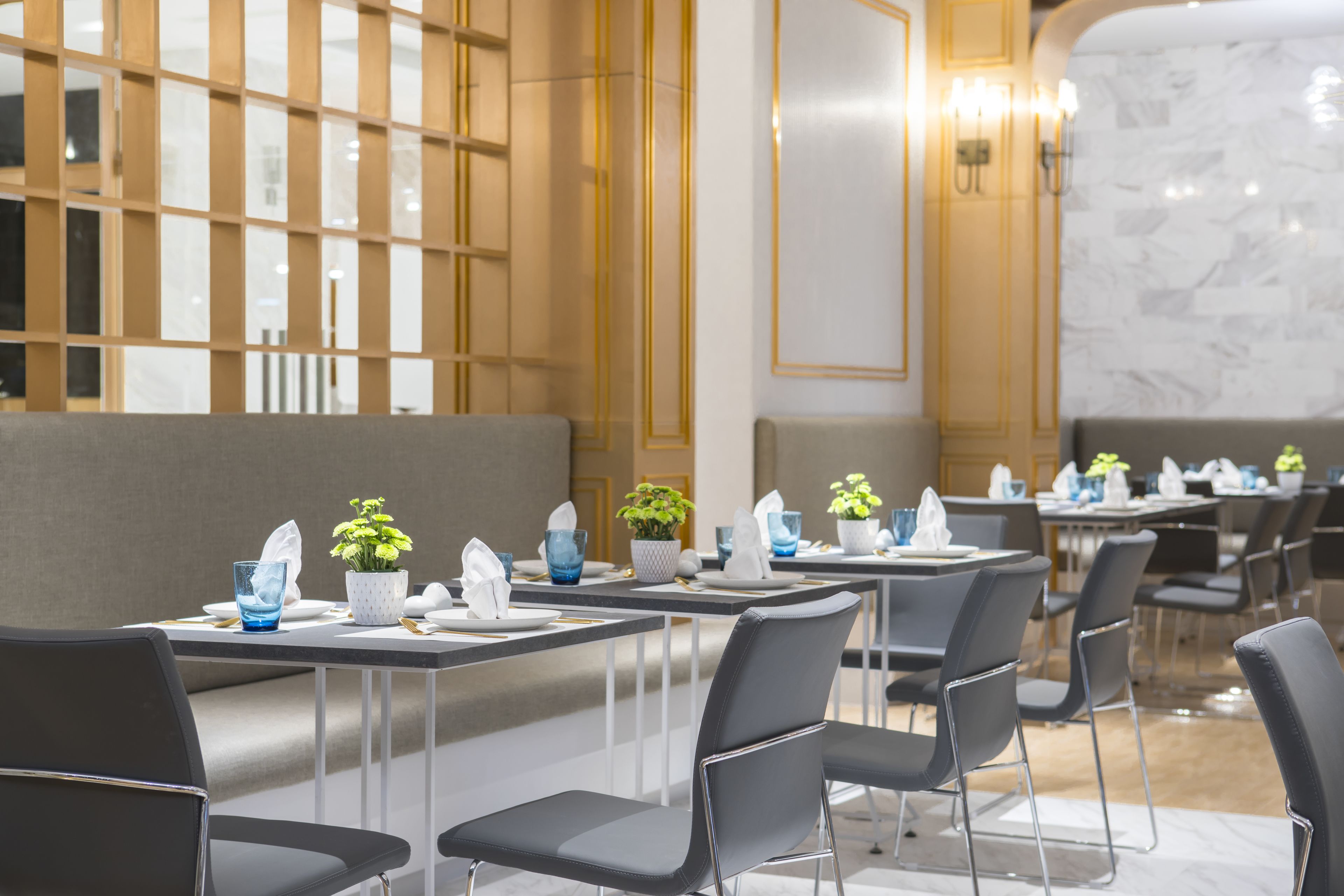 Comedor moderno con mesas dispuestas para el servicio, con un diseño limpio y minimalista, sillas grises y vajilla blanca.
