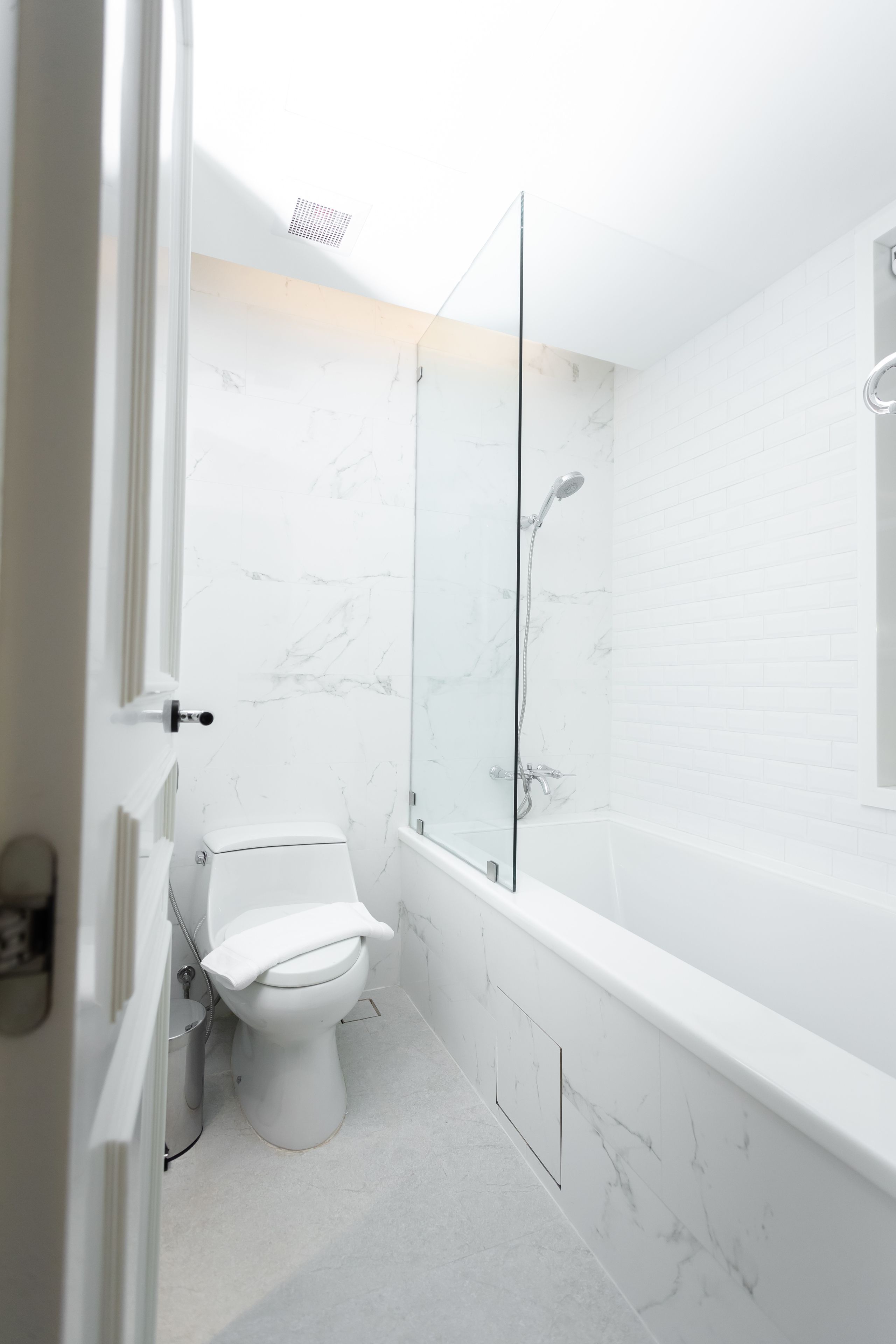 A modern bathroom with a toilet, a glass-enclosed shower, and a bathtub.