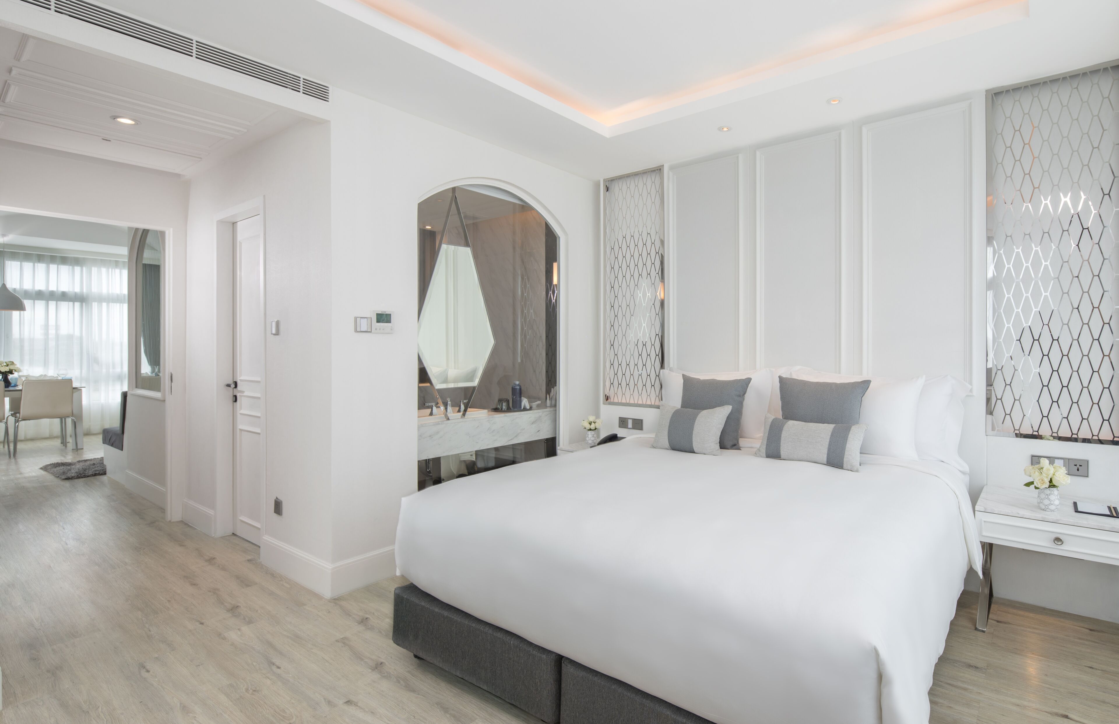 A modern bedroom with a large bed, a walk-in closet, and a bathroom with a glass shower enclosure.
