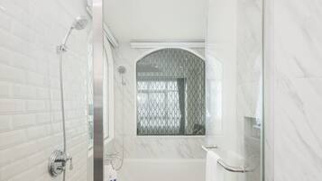 A modern bathroom with a glass shower enclosure, a bathtub, and a toilet.
