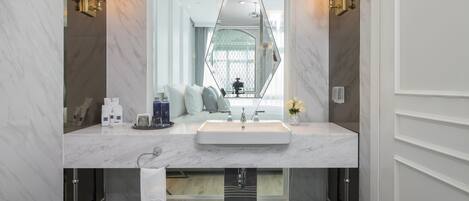 Un baño moderno con un espejo grande, un lavamanos blanco y un suelo de mármol negro.