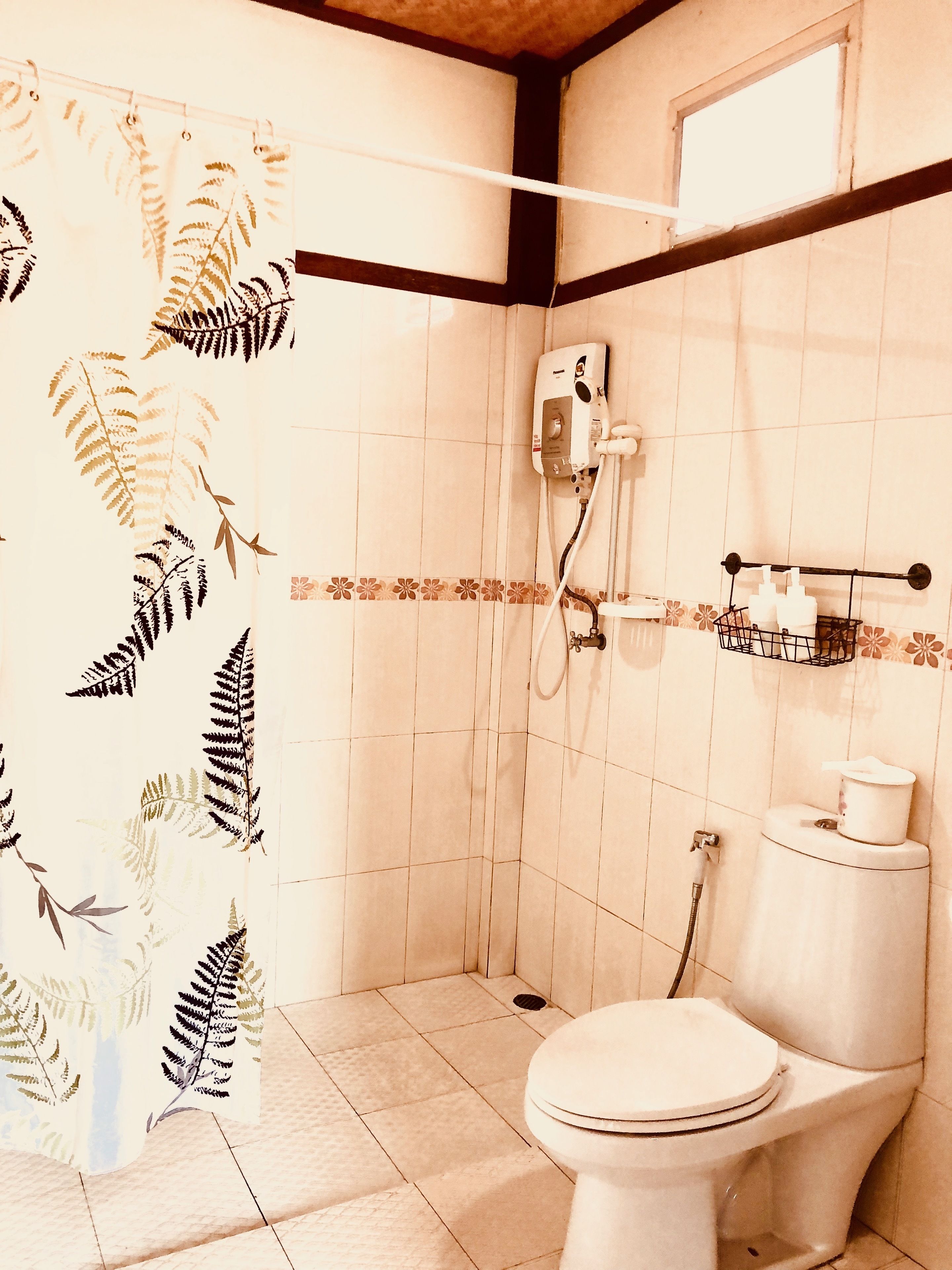 A bathroom with a shower, toilet, and a towel rack.