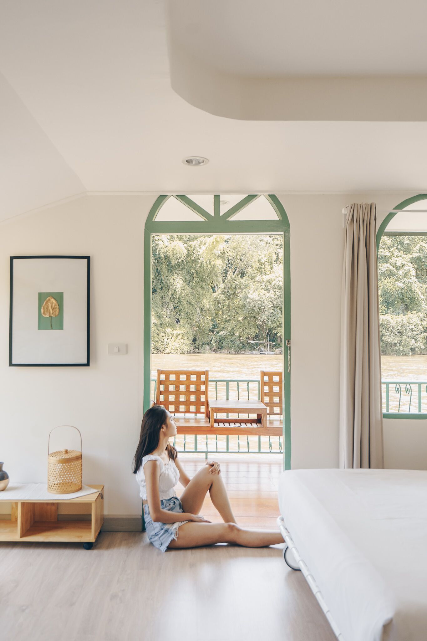 Una habitación con una cama, un banco de madera afuera y un cuadro en la pared.