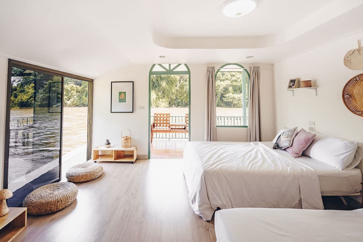 Un dormitorio con cama, una banca, una mesita y vistas a un espacio exterior.