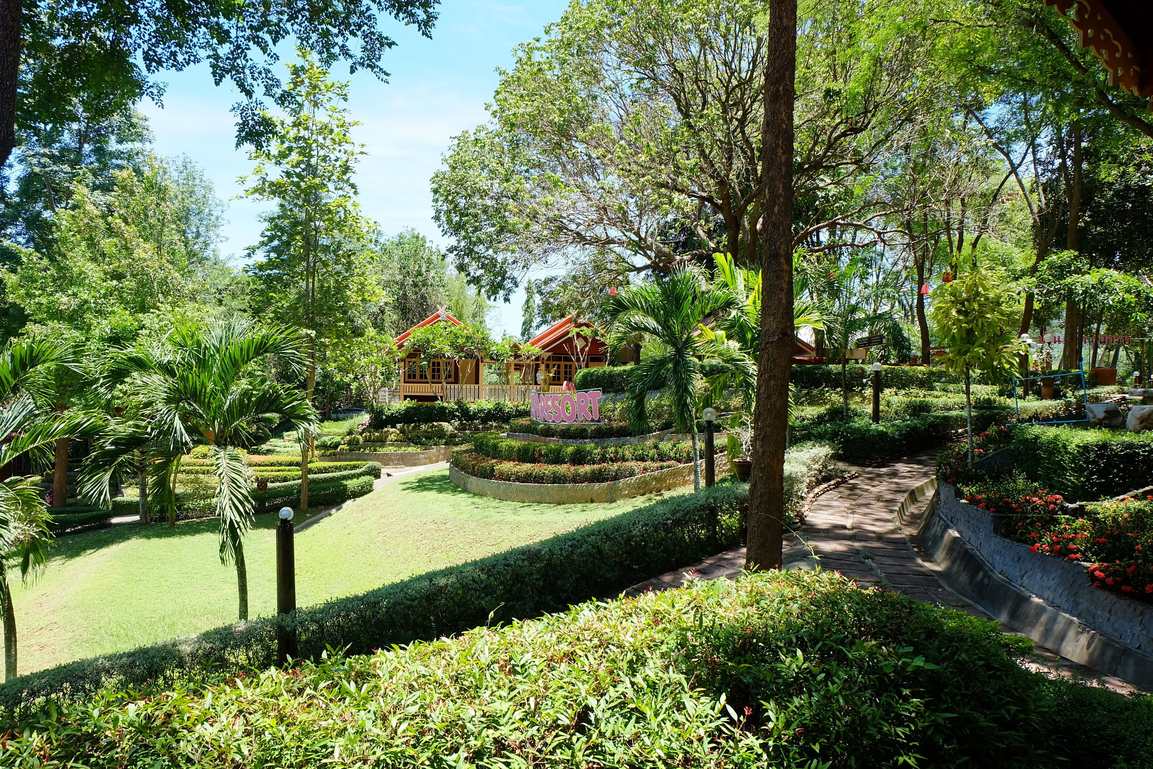 A resort with a well-maintained garden, a central pathway, and a sign indicating the name of the resort.