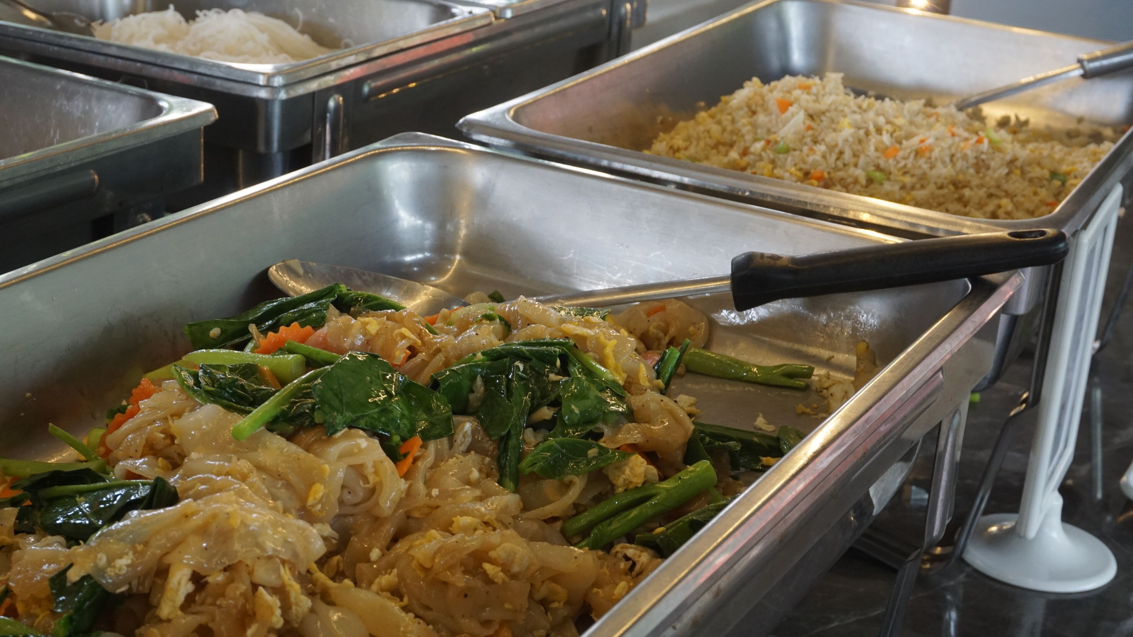 A buffet with various dishes including stir-fried vegetables, fried rice, and noodles.