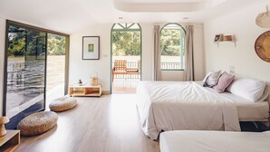 A bedroom with a large window, a bed, a bedside table, and a view of a balcony. - Baanpufa Resort (Sai Yok)