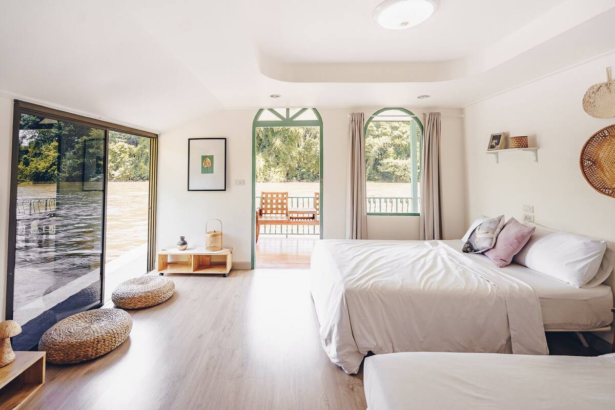 Un dormitorio con una ventana grande, una cama, una mesita de noche y vistas a un balcón.