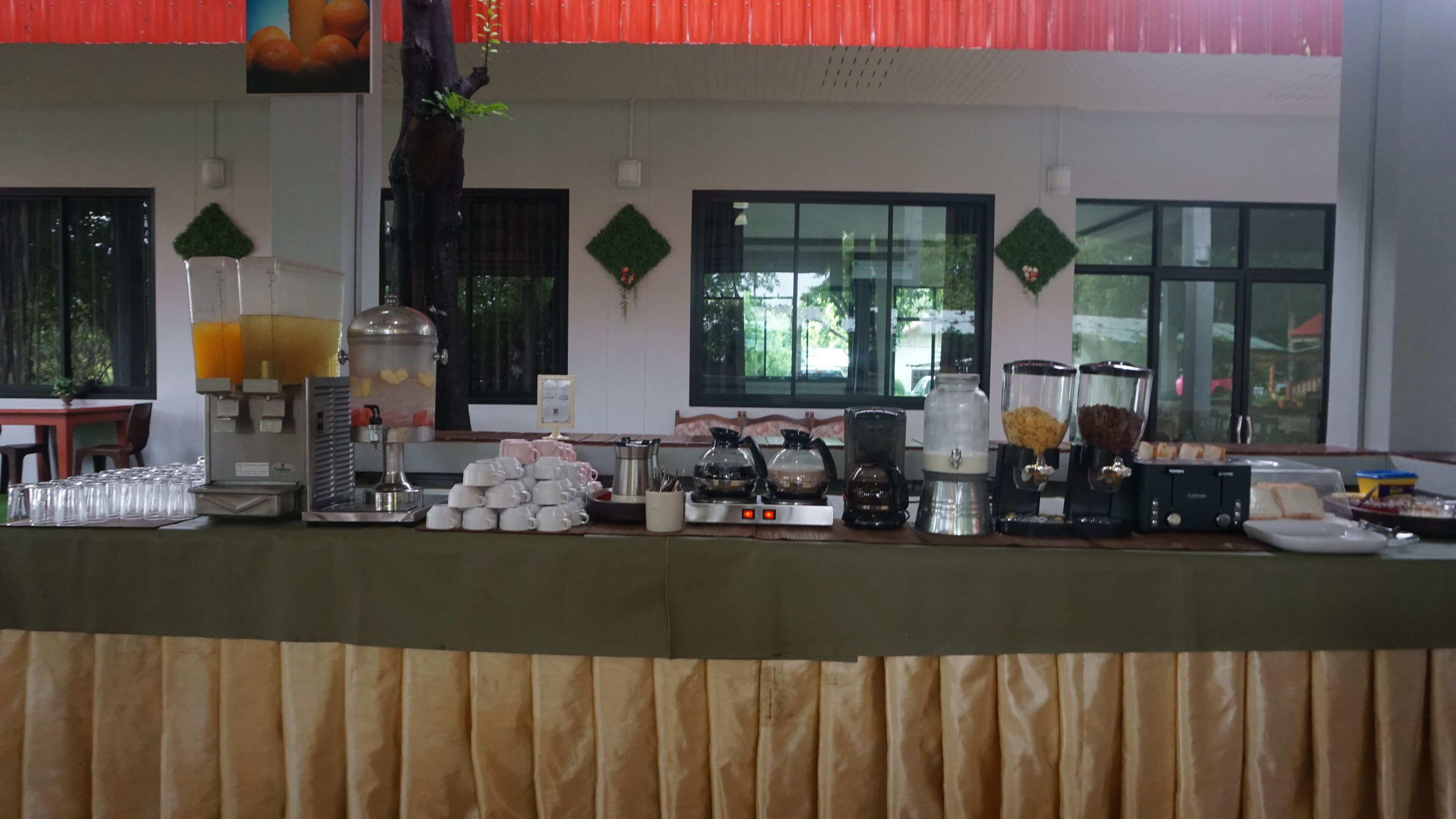 Un'area buffet con diversi distributori di cibo e bevande, tra cui un distributore di punch alla frutta, macchine per il caffè e un distributore di pane.