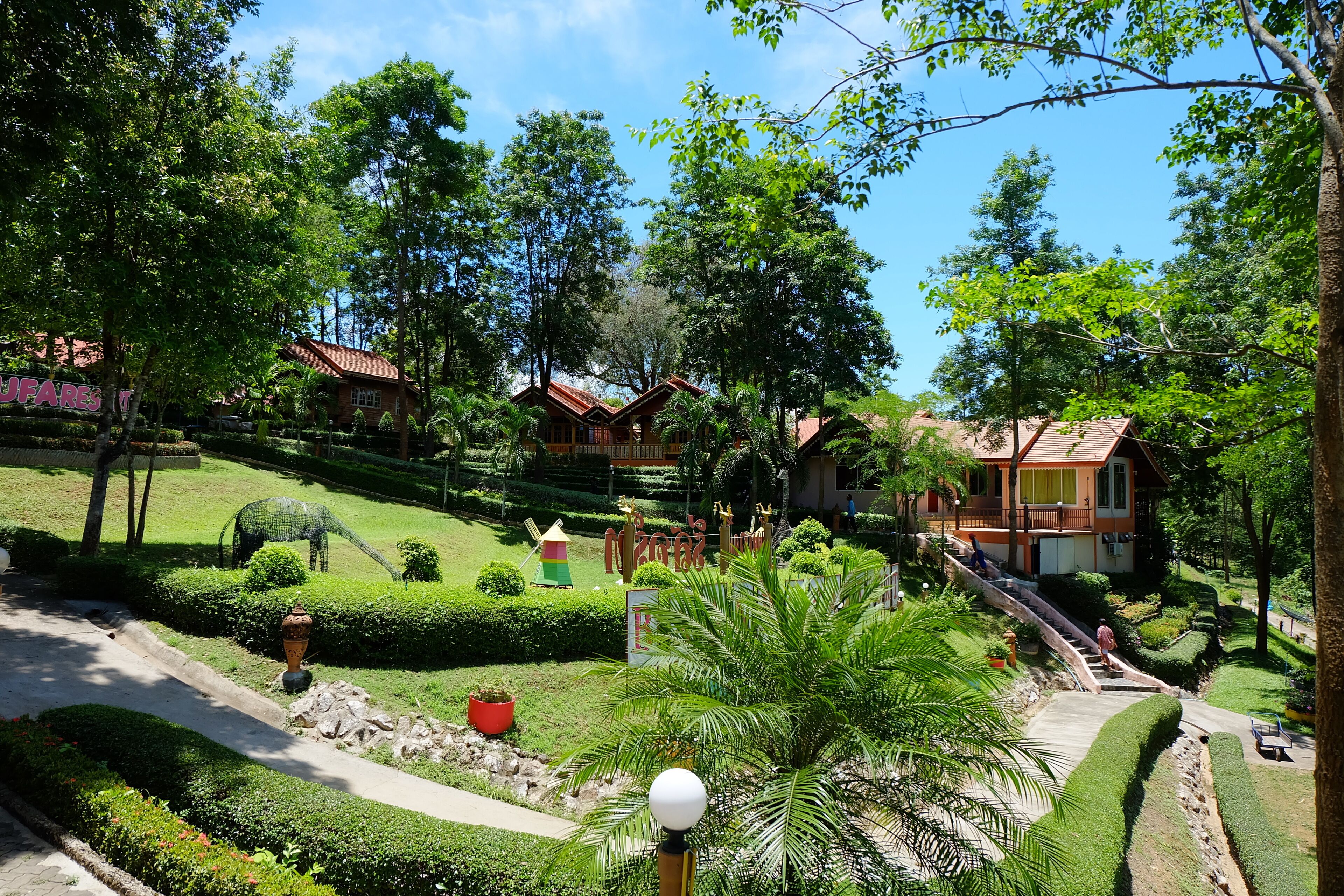 Un jardín bien cuidado con senderos, una variedad de plantas y varias casas de madera con tejados rojos.