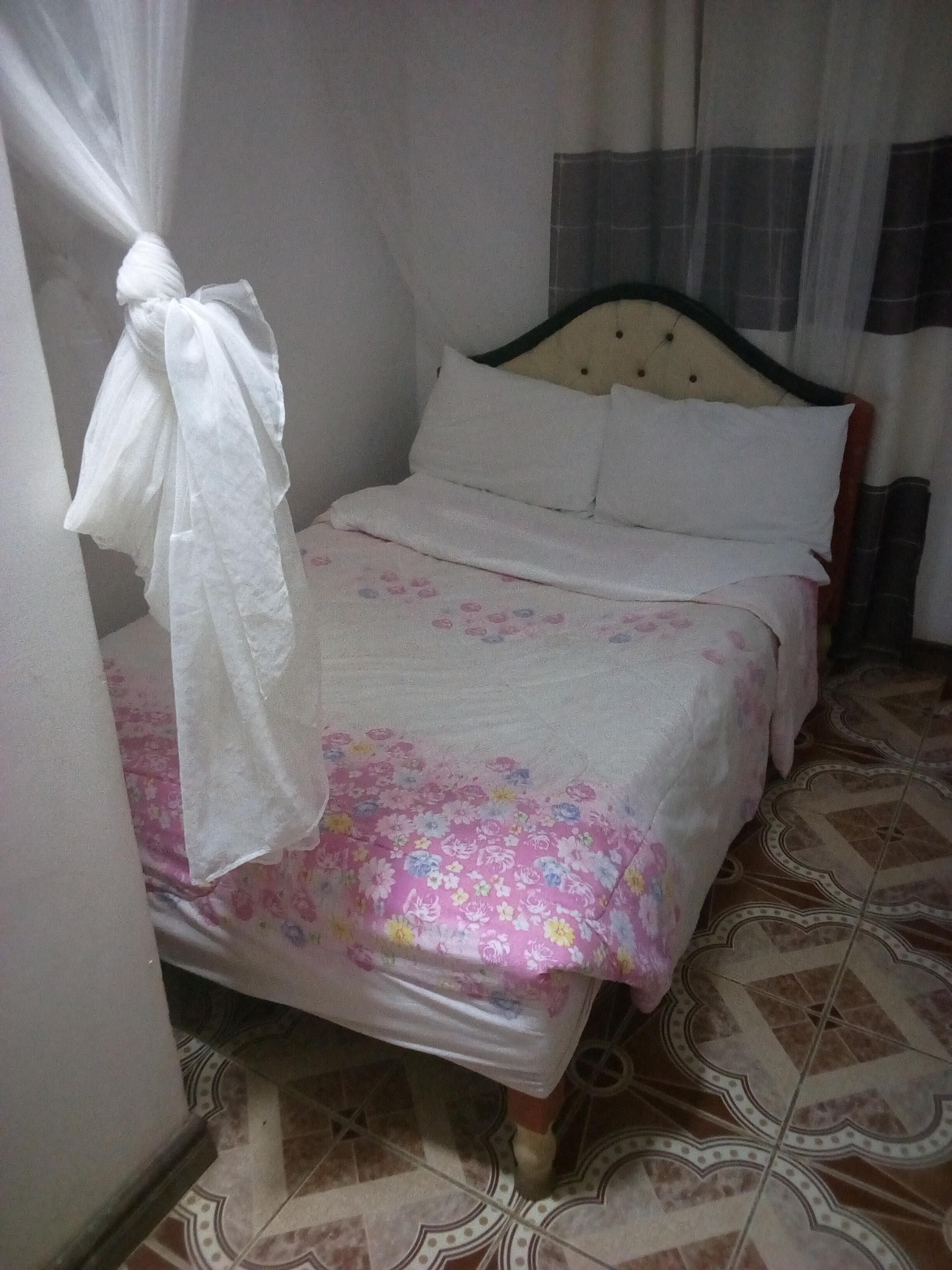 A bed with a floral bedspread, a white pillow, and a headboard.