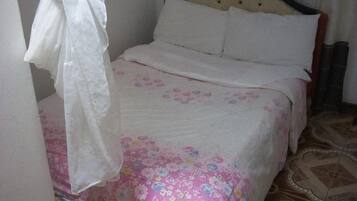 A bed with a floral bedspread, a white pillow, and a headboard.