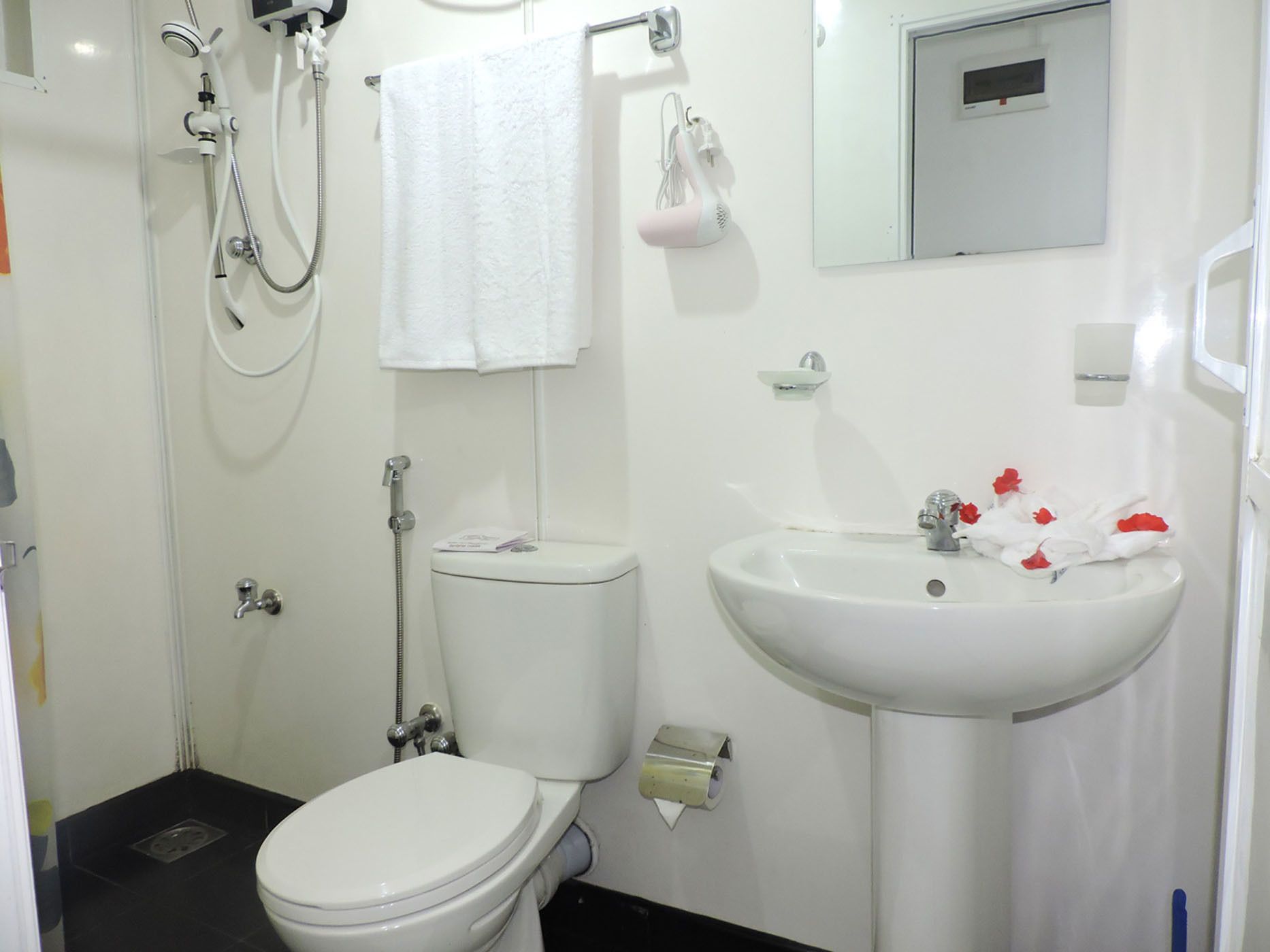 A bathroom with a toilet, a sink, a shower, and a towel hanging on the wall.