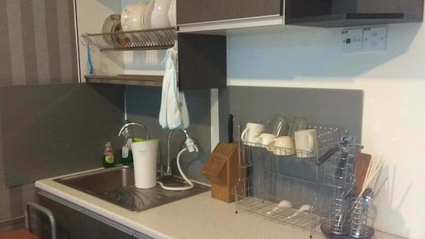 Una cocina compacta con armarios oscuros, una encimera blanca y un escurreplatos.
