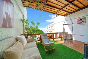A covered patio with a wooden swing chair, a cushioned sofa, and a small table. - Tian Yan Mountains (Jiaoxi)