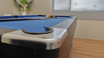 A pool table with a blue felt surface, a pool cue, and a set of billiard balls.