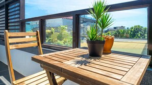 A wooden table with a potted plant and a terracotta pot on a balcony with a city view. - Tian Yan Mountains (Jiaoxi)