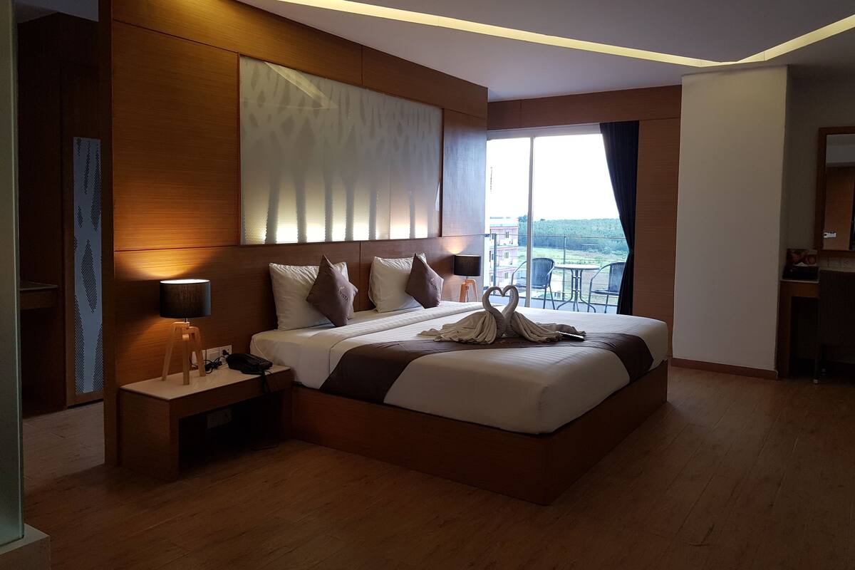 A modern hotel room with a large bed, a desk, and a view of the outdoors.