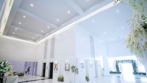 A spacious lobby with a high ceiling, recessed lighting, and a large floral arrangement. - The Vista Hotel (Sadao)