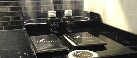 A black countertop with three bottles of VISTA shower cap and two boxes of VISTA shower cap.