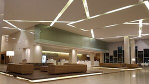 A modern hotel lobby with a reception desk, seating area, and a glass balustrade. - The Vista Hotel (Sadao)