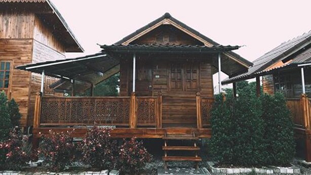 Ein traditionelles Holzhaus mit Balkon und hölzernem Zaun.