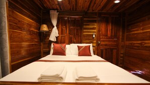 Ein holzgetäfeltes Zimmer im Blockhausstil mit einem Bett, weißen Leinen und einem Baldachin.