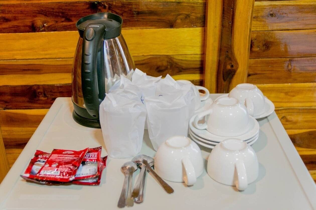 Ein Frühstücksangebot mit Kaffeemaschine, Tassen, Tellern und Besteck auf einer Tablett.