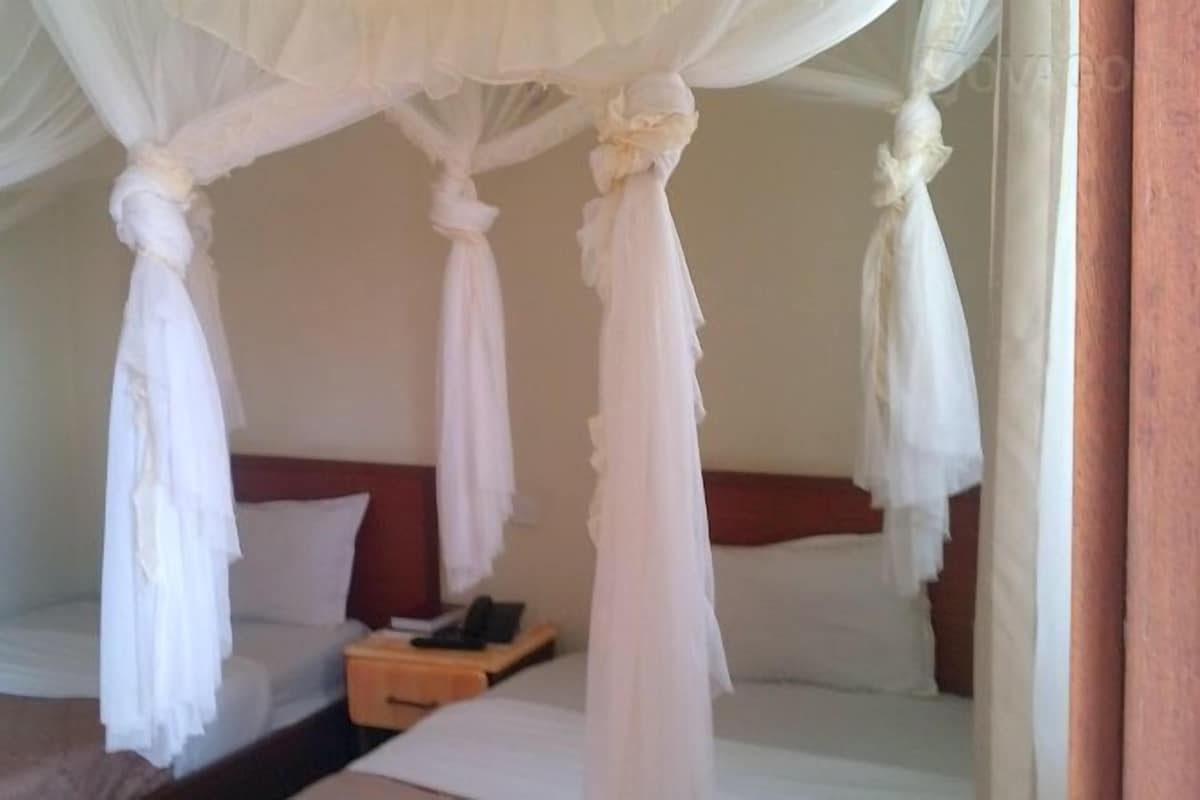 A bedroom with a canopy bed, a bedside table, and a nightstand.