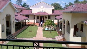 A building with a central courtyard, surrounded by two-story structures with red roofs. - Bondo Pride Hotel (Bondo)