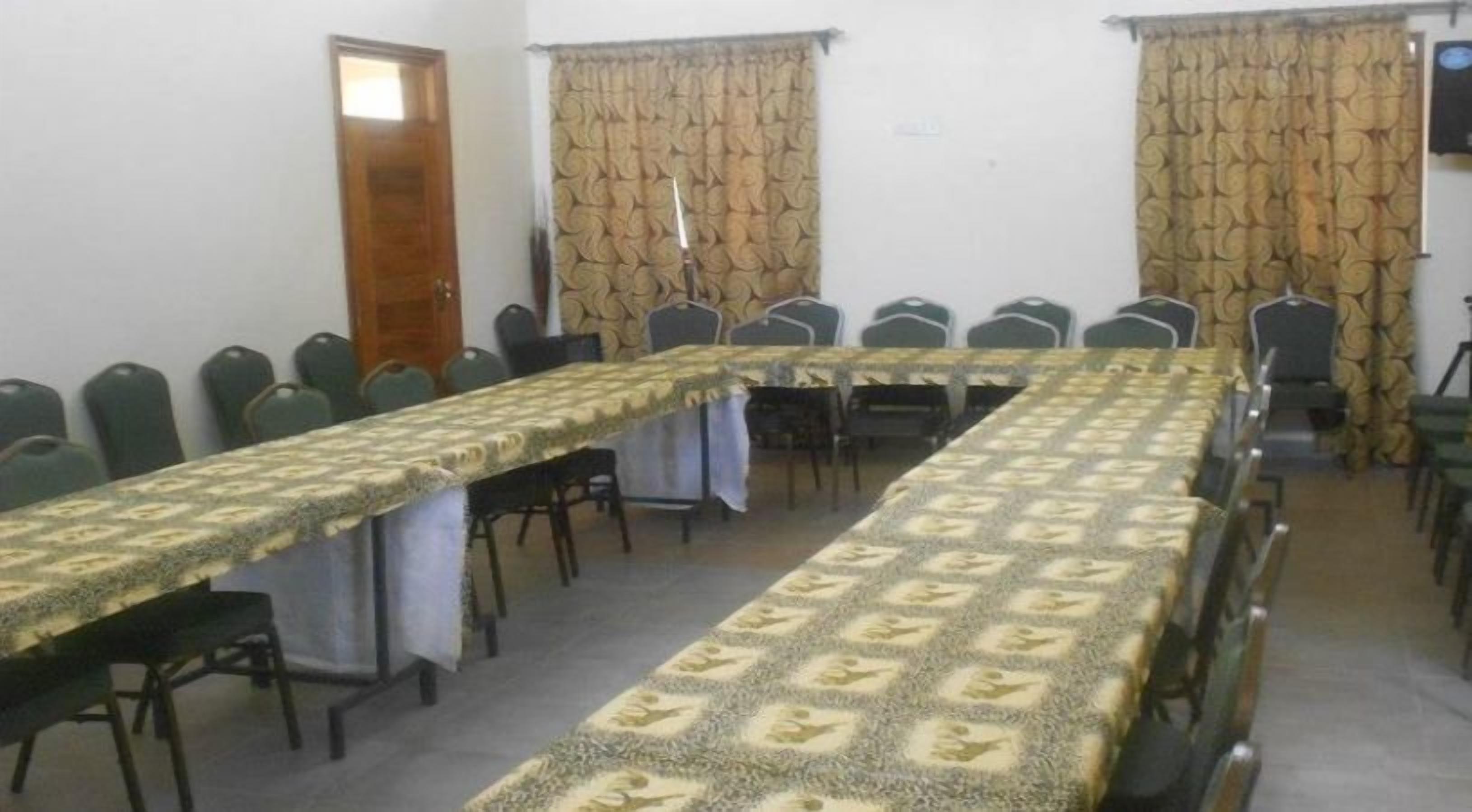 A conference room with a long table, chairs, and patterned curtains.